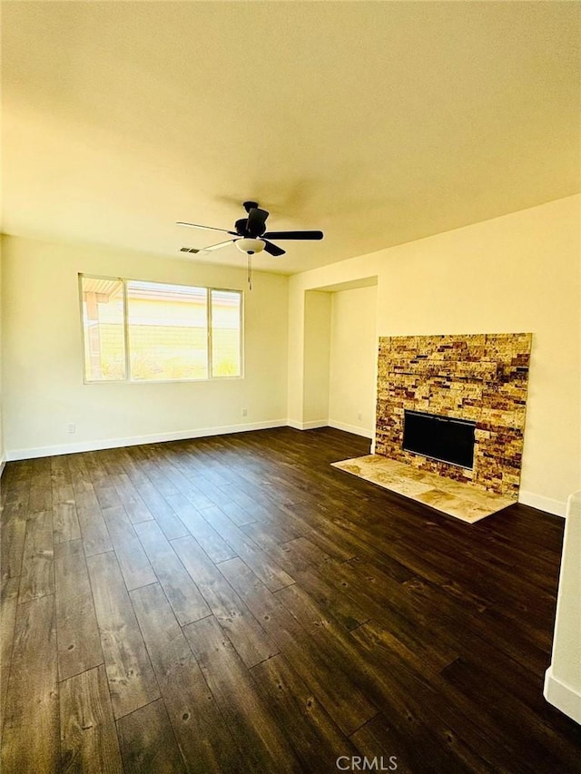 65565 Acoma Ave Unit 68, Desert Hot Springs, CA 92240 - unfurnished living room featuring visible vents, baseboards, a stone fireplace, a ceiling fan, and dark wood-type flooring