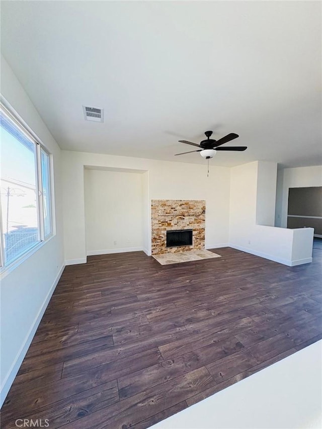 65565 Acoma Ave Unit 68, Desert Hot Springs, CA 92240 - unfurnished living room featuring baseboards, dark wood-style floors, a ceiling fan, a fireplace with flush hearth, and visible vents