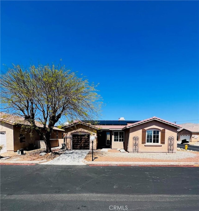 65565 Acoma Ave Unit 68, Desert Hot Springs, CA 92240 - single story home featuring roof mounted solar panels, a tiled roof, stucco siding, a garage, and driveway