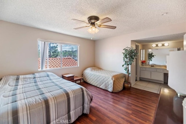bedroom featuring ensuite bathroom, ceiling fan, light wood-style floors, and a textured ceiling