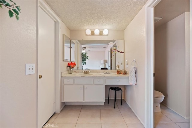 bathroom featuring baseboards, toilet, a textured ceiling, vanity, and tile patterned floors
