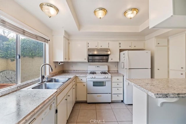 kitchen featuring white appliances, light tile patterned floors, light countertops, a raised ceiling, and a sink