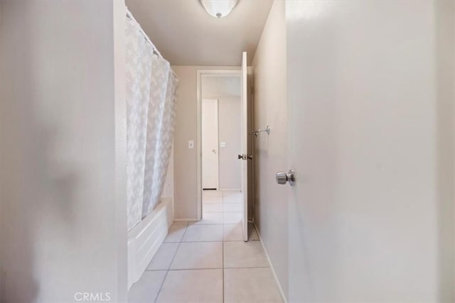 hallway with light tile patterned floors and baseboards