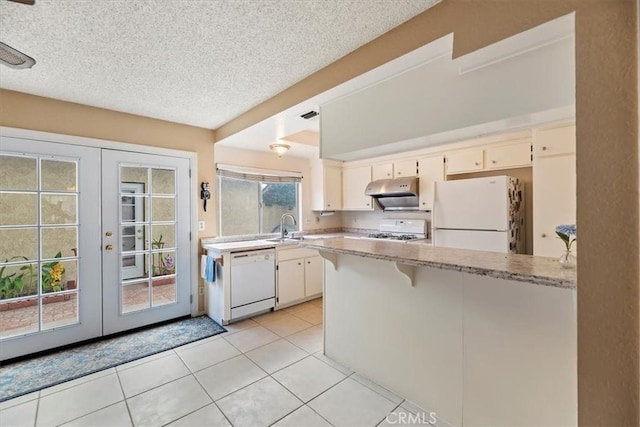 kitchen featuring a sink, white appliances, a peninsula, under cabinet range hood, and french doors