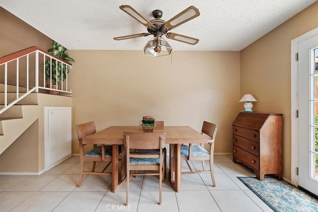 tiled dining room featuring a wealth of natural light, stairway, a textured ceiling, and ceiling fan