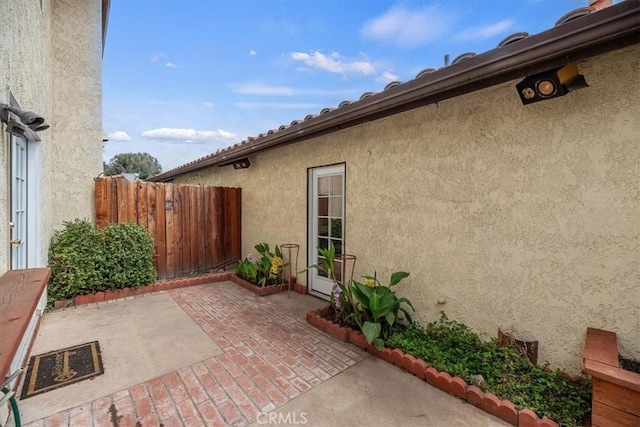 view of home's exterior with a patio area, stucco siding, and fence