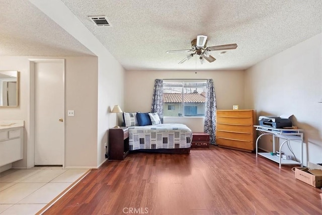 bedroom with visible vents, wood finished floors, and a textured ceiling