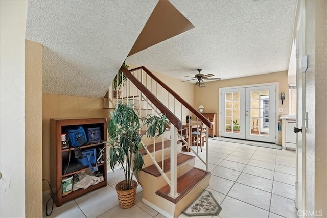 stairs with a textured wall, french doors, a textured ceiling, and ceiling fan