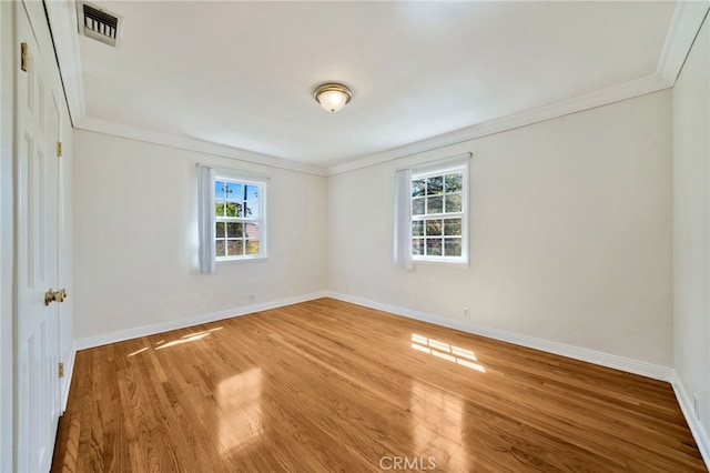 empty room featuring visible vents, baseboards, crown molding, and wood finished floors