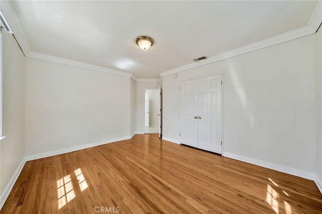 unfurnished bedroom with ornamental molding, visible vents, light wood-style flooring, and baseboards