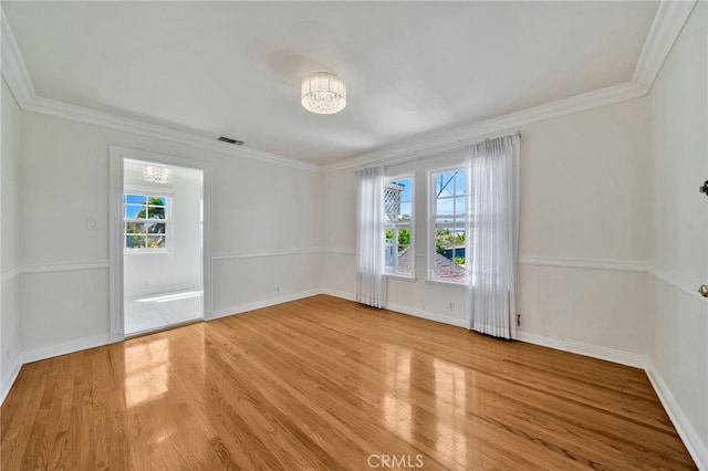 empty room with ornamental molding, visible vents, wood finished floors, baseboards, and a notable chandelier