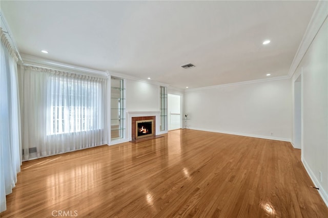 unfurnished living room with baseboards, ornamental molding, recessed lighting, visible vents, and wood finished floors