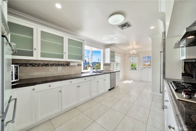kitchen featuring wall chimney exhaust hood, tasteful backsplash, ornamental molding, visible vents, and stainless steel appliances