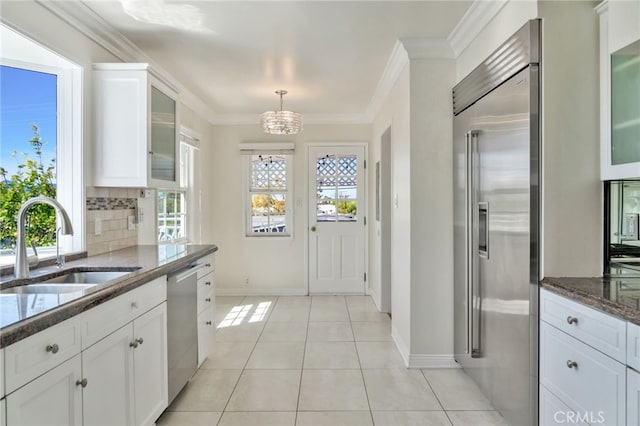 kitchen featuring dark stone countertops, a sink, ornamental molding, appliances with stainless steel finishes, and backsplash