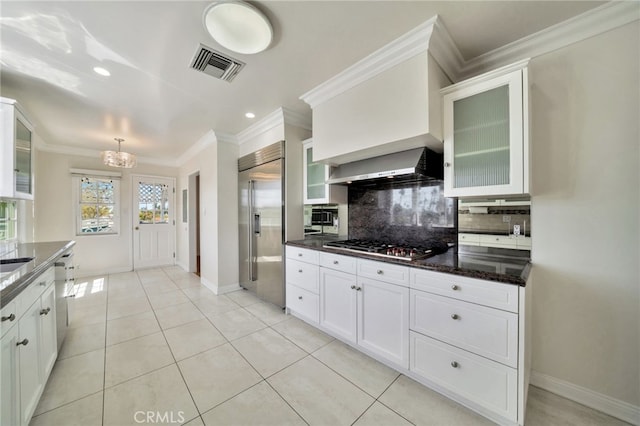 kitchen featuring wall chimney range hood, visible vents, stainless steel appliances, decorative backsplash, and a notable chandelier