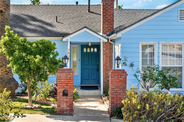 entrance to property with a chimney and roof with shingles