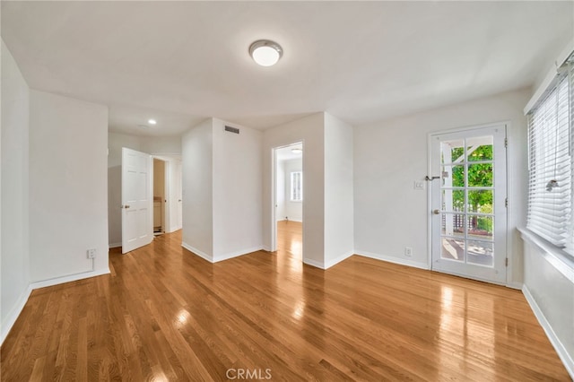 unfurnished room featuring visible vents, baseboards, and wood finished floors