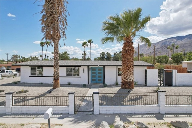 845 W Gateway Dr, Palm Springs, CA 92262 - view of front facade featuring stucco siding, a mountain view, a fenced front yard, and a gate
