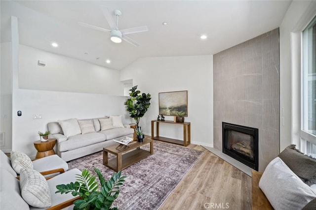 living room with recessed lighting, a tiled fireplace, a ceiling fan, lofted ceiling, and wood finished floors