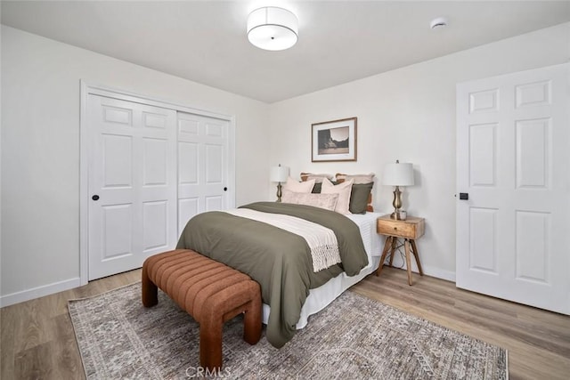 bedroom with a closet, baseboards, and wood finished floors