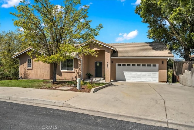 ranch-style home with a tiled roof, stucco siding, fence, a garage, and concrete driveway