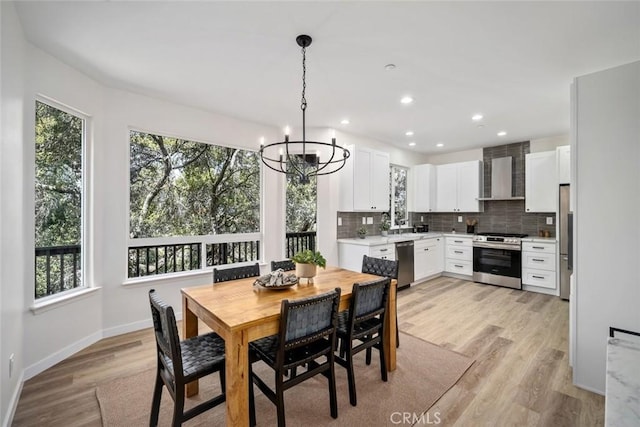 dining area featuring baseboards, light wood-type flooring, a chandelier, and a healthy amount of sunlight