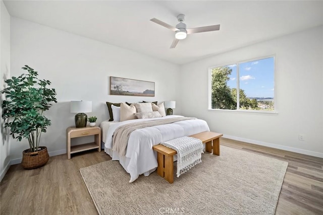 bedroom featuring wood finished floors, baseboards, and a ceiling fan