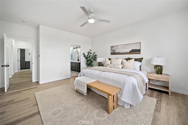 bedroom with light wood finished floors, ensuite bathroom, baseboards, and ceiling fan