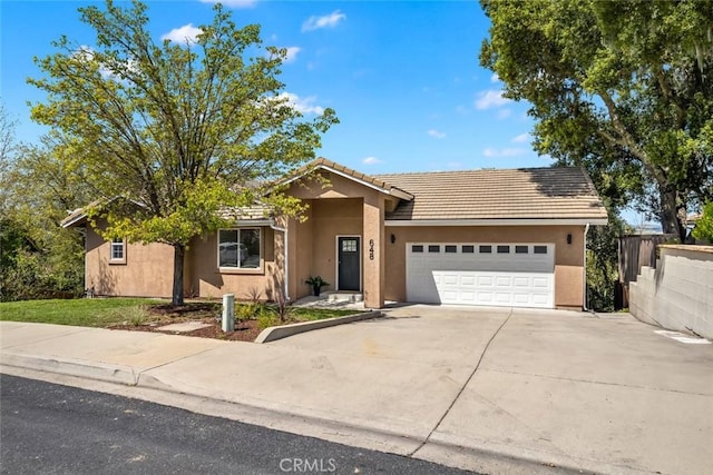 view of front of home featuring an attached garage, a tiled roof, driveway, and stucco siding