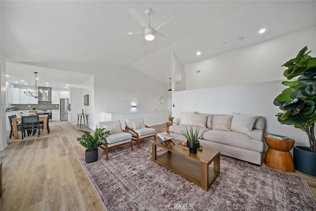 living area featuring recessed lighting, vaulted ceiling, light wood-style floors, and ceiling fan with notable chandelier