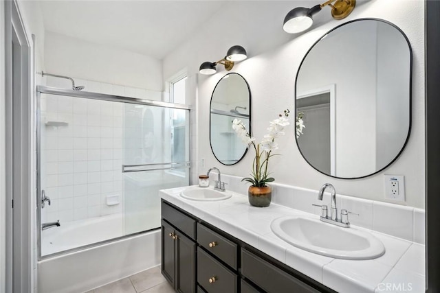 bathroom featuring shower / bath combination with glass door, double vanity, a sink, and tile patterned flooring