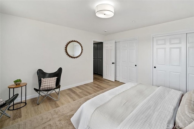 bedroom with multiple closets, wood finished floors, and baseboards