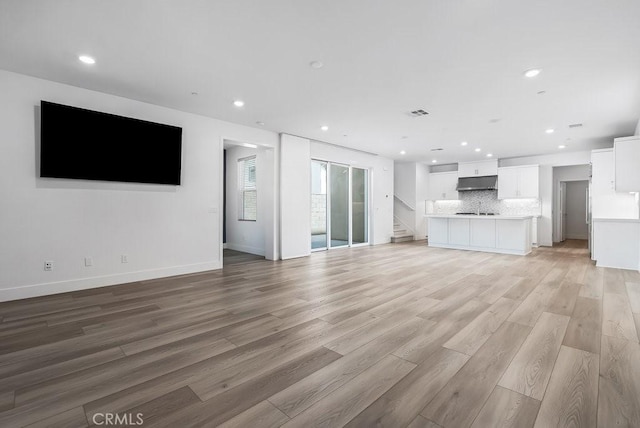 120 Zawn, Irvine, CA 92618 - unfurnished living room with stairway, recessed lighting, a sink, light wood finished floors, and baseboards