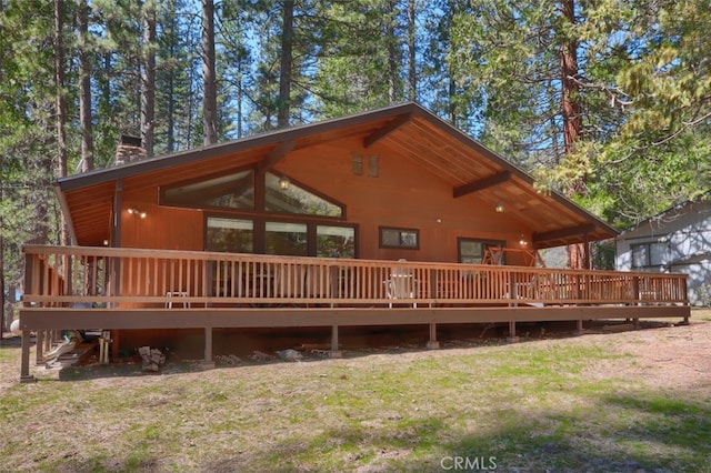 back of property featuring a chimney, a deck, and a yard