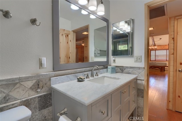 half bath featuring tile walls, a wainscoted wall, and visible vents