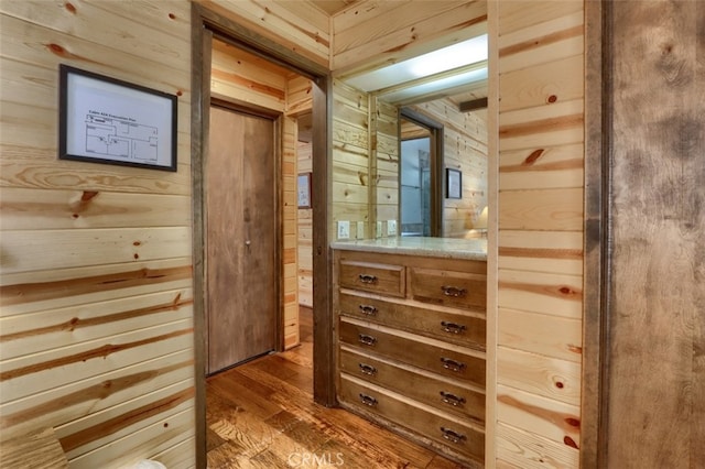 bathroom with vanity, wooden walls, and wood finished floors
