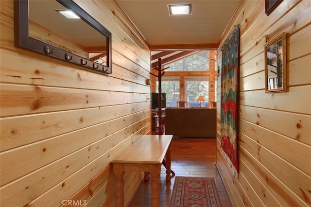 hallway with hardwood / wood-style floors, wood walls, and lofted ceiling
