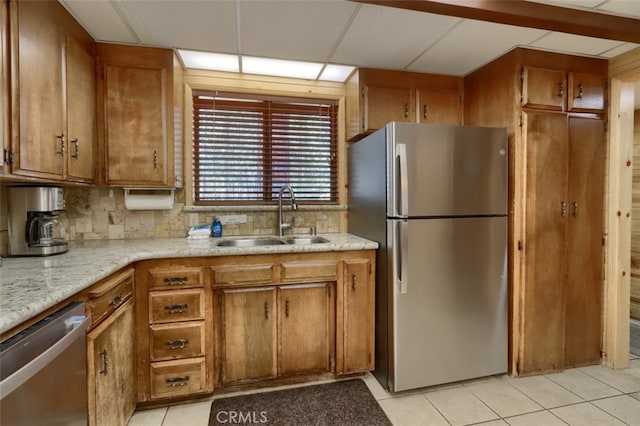 kitchen with a sink, tasteful backsplash, appliances with stainless steel finishes, and brown cabinetry