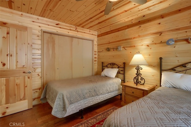 bedroom with a closet, wood finished floors, wooden walls, and wood ceiling