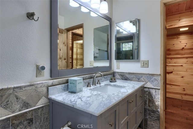 bathroom featuring a wainscoted wall, vanity, and tile walls