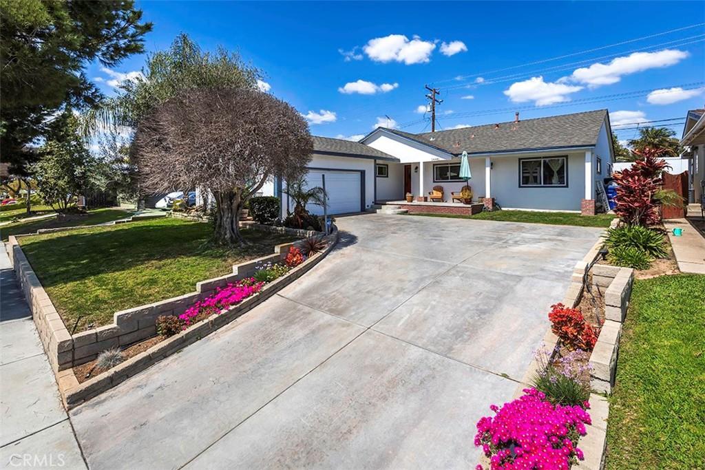 ranch-style house with driveway, a garage, a front lawn, and stucco siding