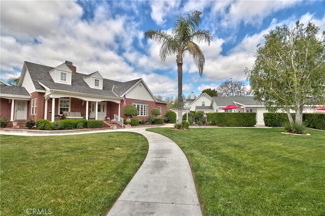 41548 Hutchison Ct, Murrieta, CA 92562 - cape cod house featuring brick siding, a front lawn, covered porch, and roof with shingles