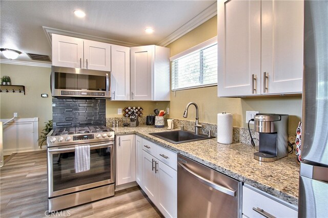 41548 Hutchison Ct, Murrieta, CA 92562 - kitchen featuring appliances with stainless steel finishes, a sink, crown molding, white cabinetry, and light stone countertops