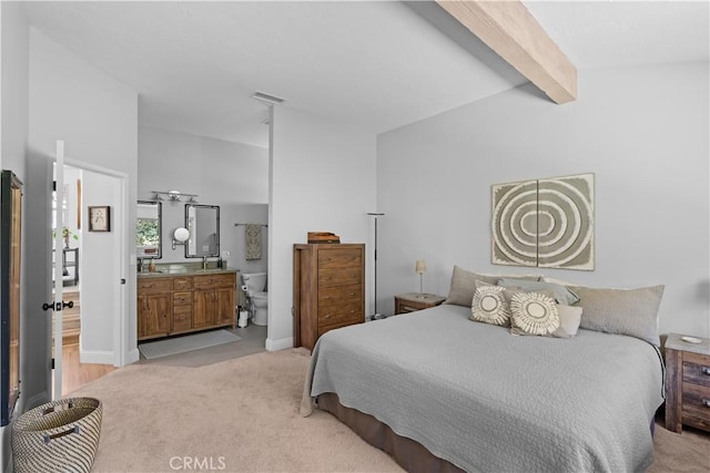 bedroom with vaulted ceiling with beams, light carpet, ensuite bath, and visible vents