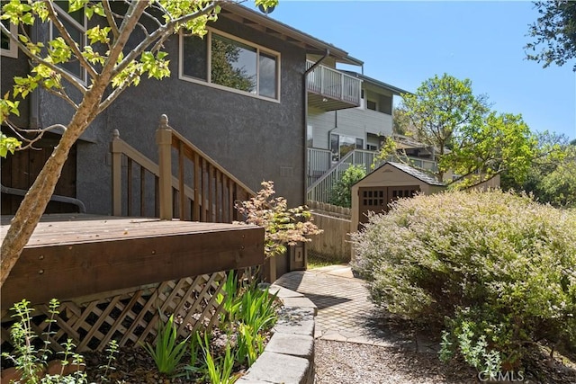 view of side of home featuring stucco siding, stairway, and a balcony