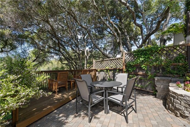 view of patio featuring fence, outdoor dining space, and a deck