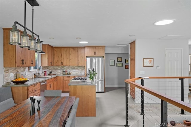 kitchen with a kitchen island, appliances with stainless steel finishes, tasteful backsplash, a sink, and light countertops