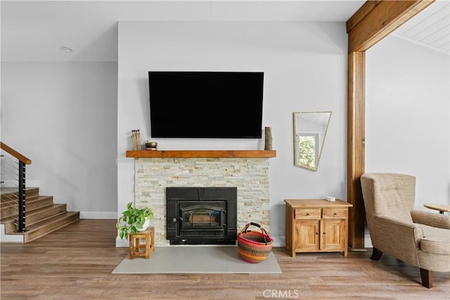 sitting room with baseboards, a stone fireplace, stairs, and wood finished floors