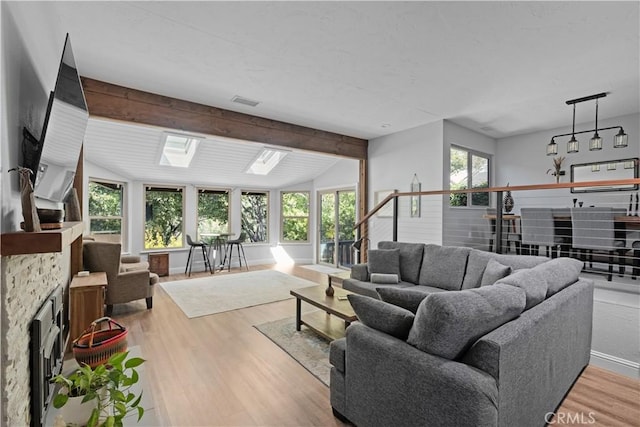 living area with visible vents, lofted ceiling with skylight, and wood finished floors