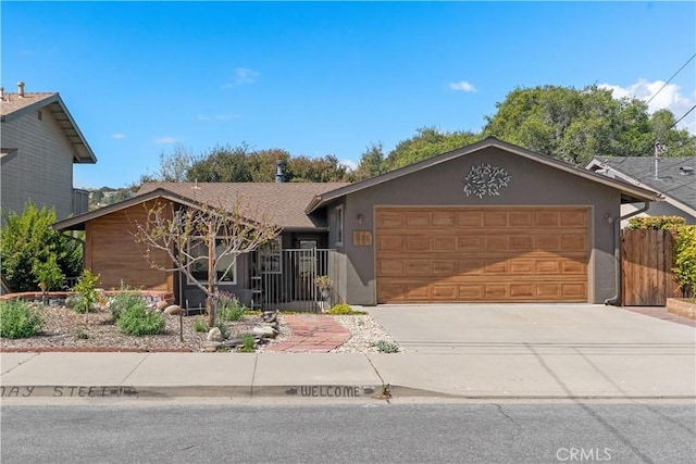 view of front of home featuring fence, an attached garage, driveway, and stucco siding